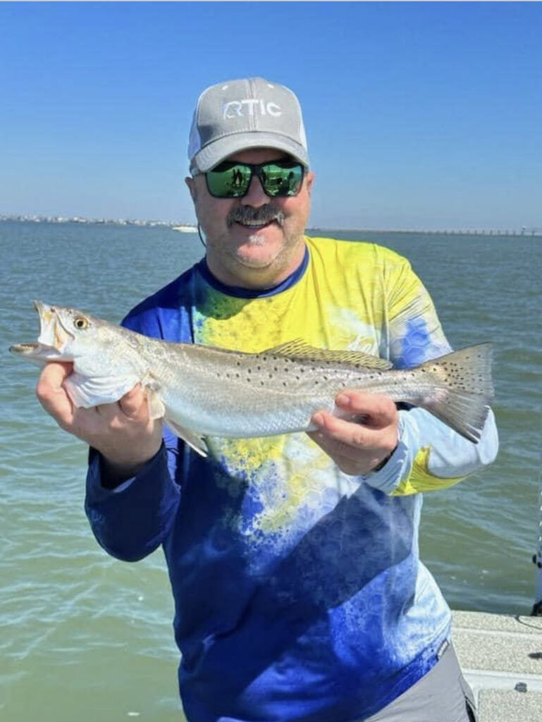 Man holds up fish caught on his trip in two hands