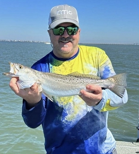 Man holds up fish caught on his trip in two hands